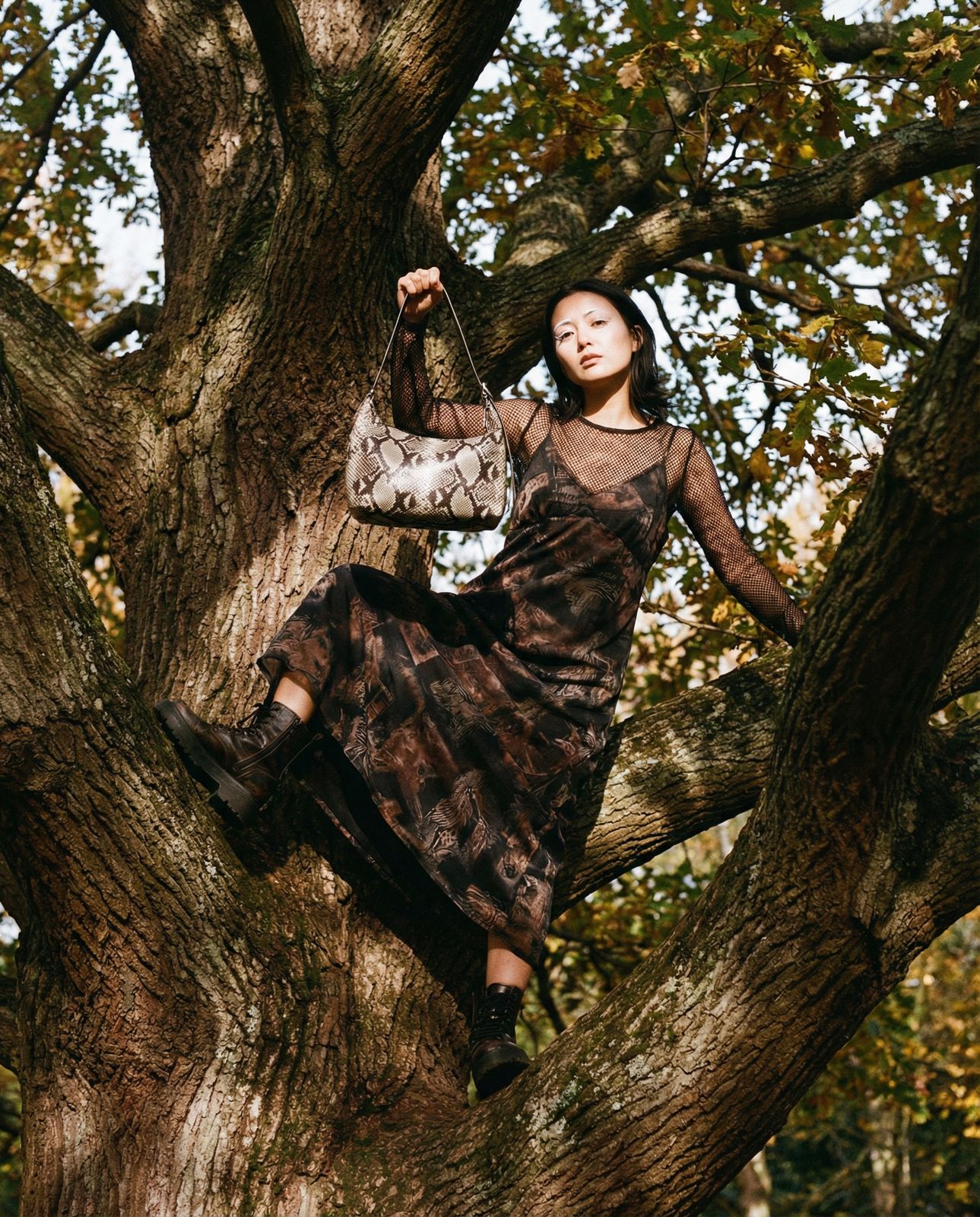 a woman sitting in a tree holding a purse