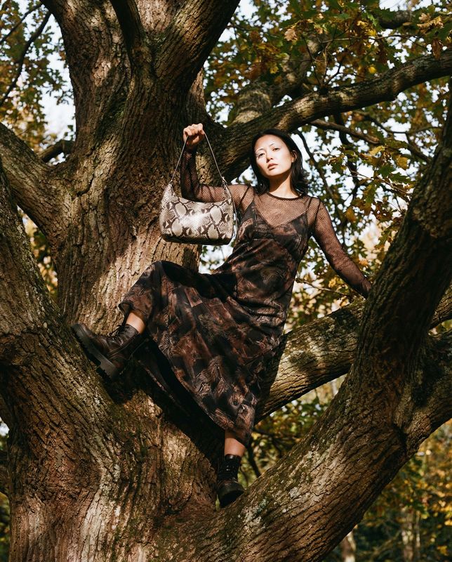 a woman sitting in a tree holding a purse