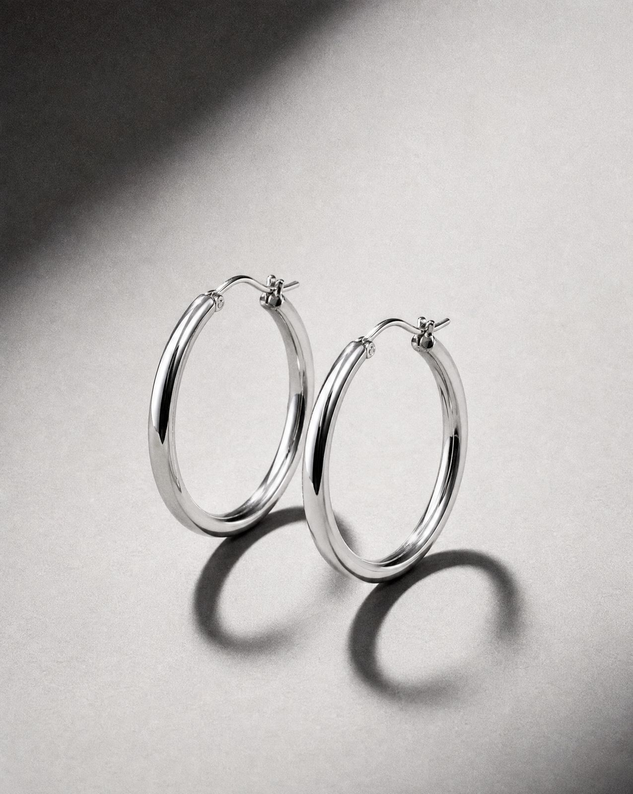 a pair of silver hoop earrings on a white surface