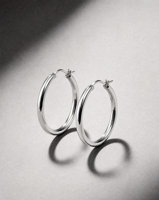 a pair of silver hoop earrings on a white surface
