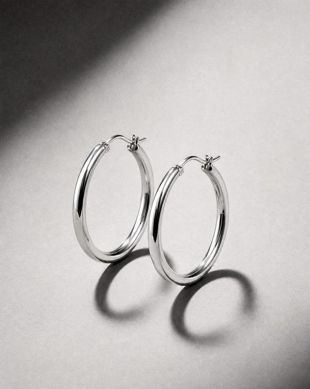 a pair of silver hoop earrings on a white surface