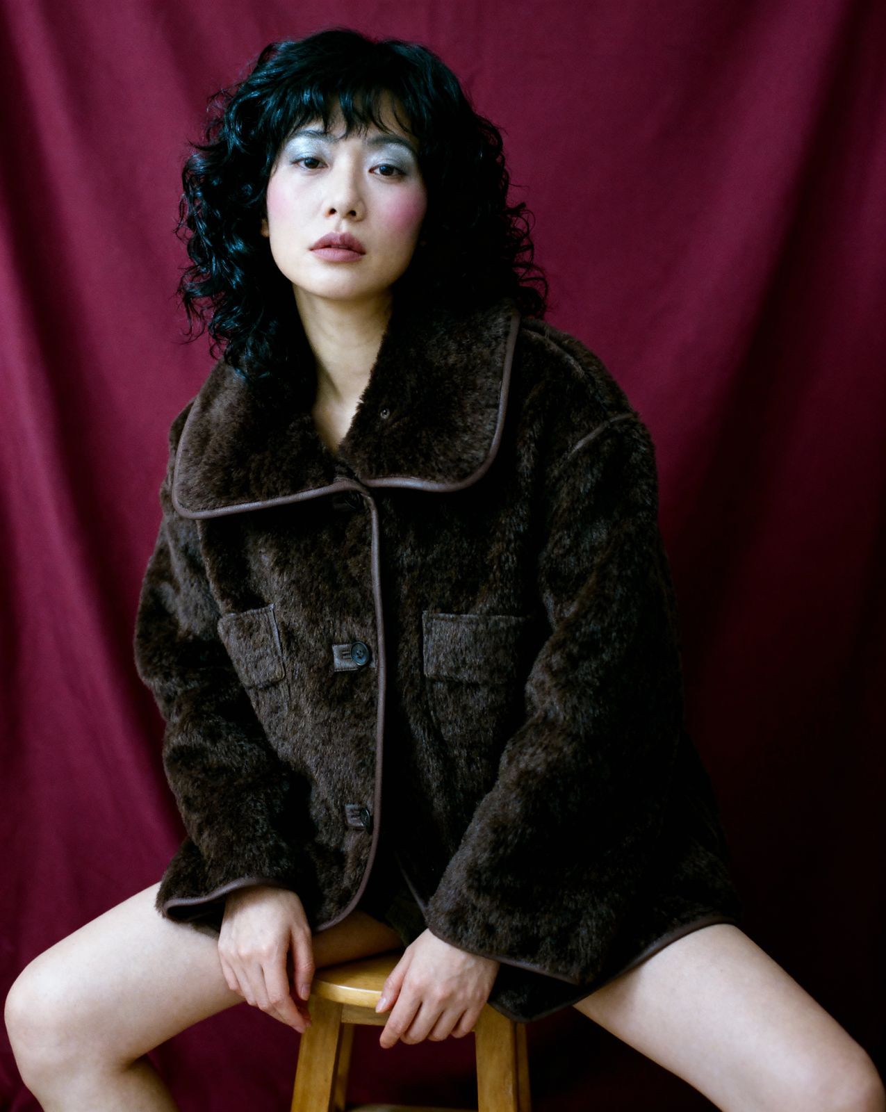 a woman sitting on top of a wooden stool