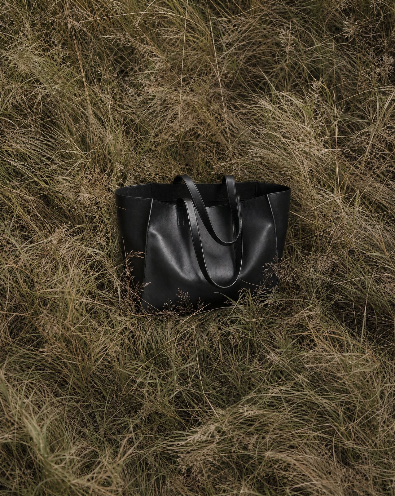 a black bag laying in a field of grass