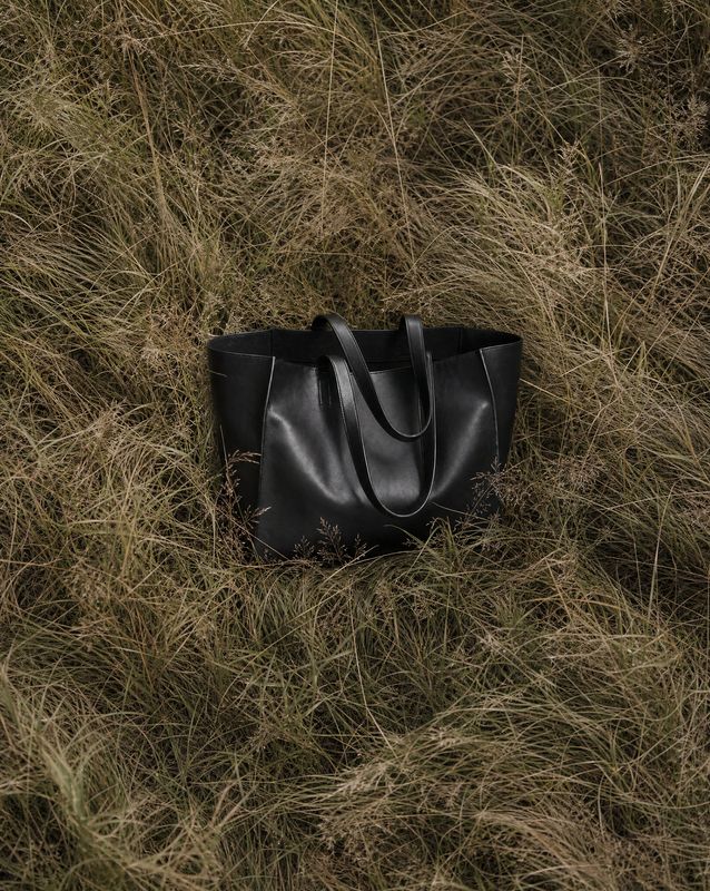 a black bag laying in a field of grass