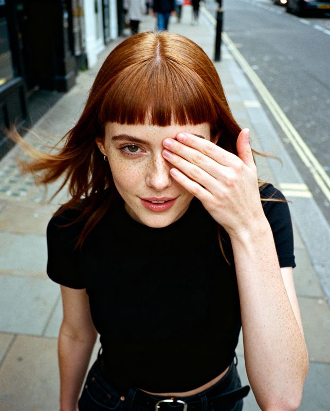 a woman with red hair is holding her hand to her face