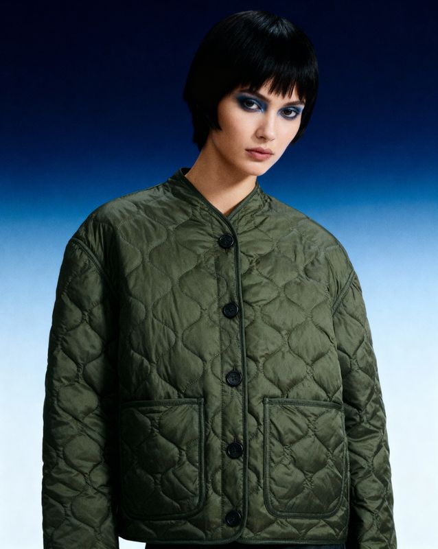 a woman wearing a green jacket and black pants