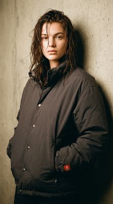 a woman leaning against a wall with her hands on her hips