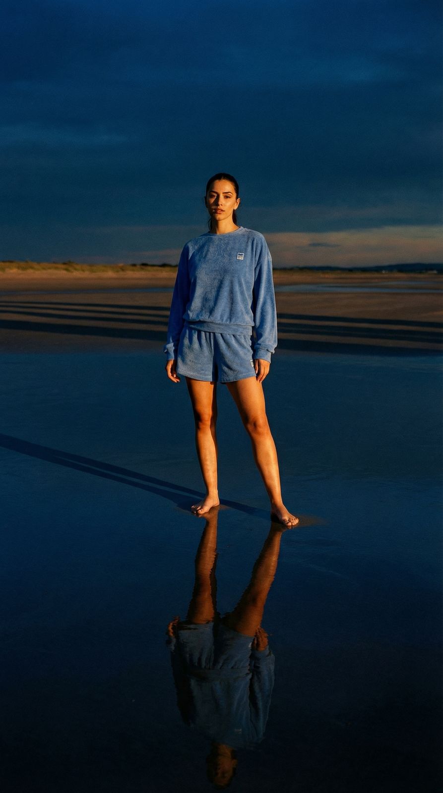 a woman standing on a beach next to a body of water