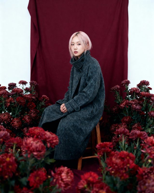 a woman sitting in a chair surrounded by flowers