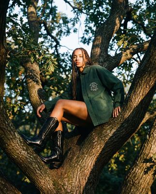 a woman sitting in a tree wearing boots