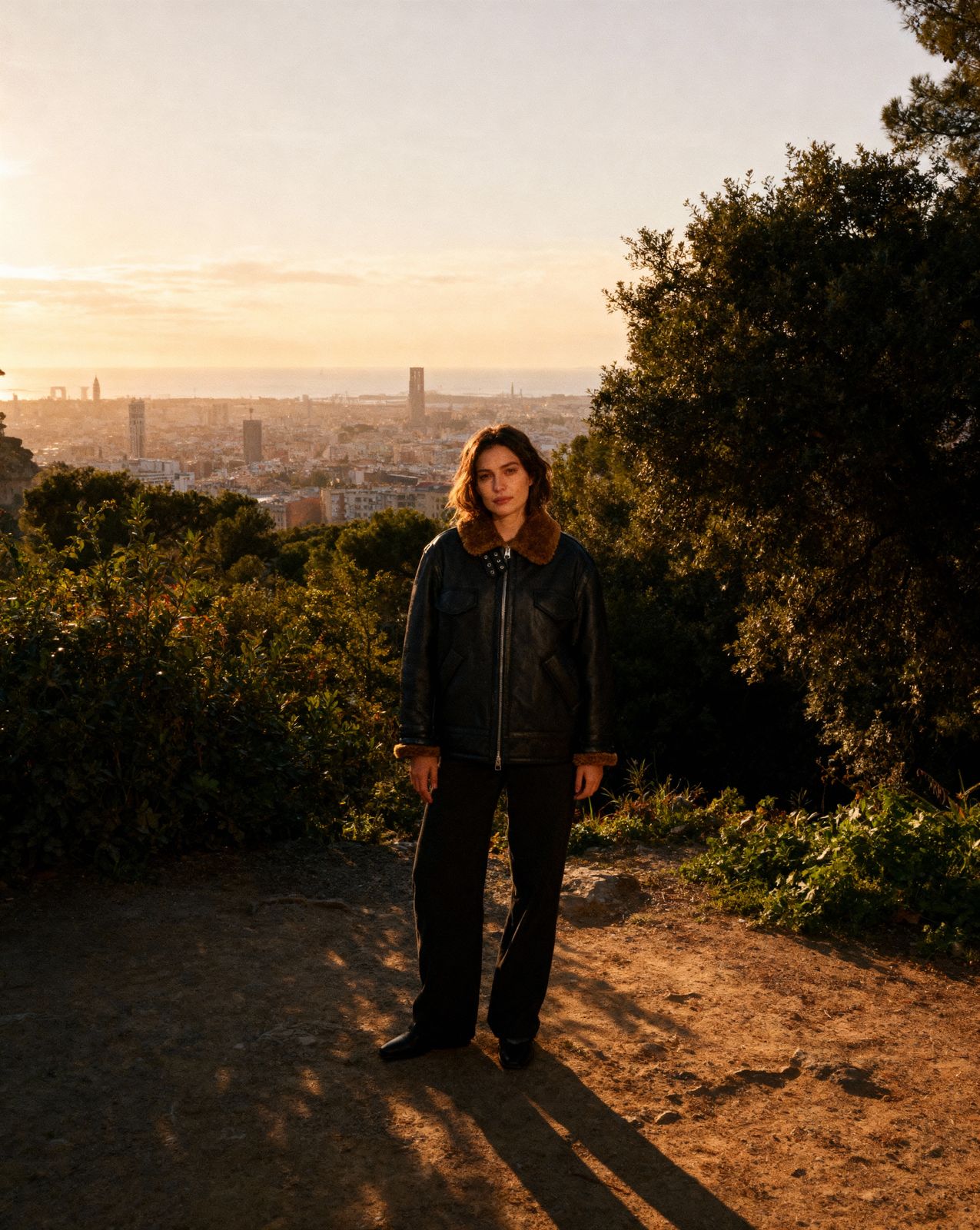 a man standing on a dirt road next to a forest