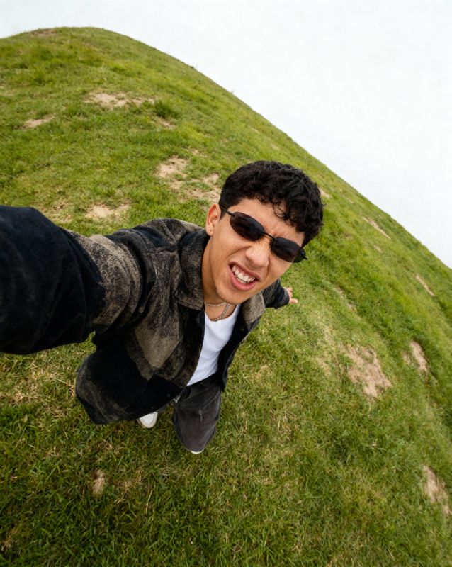 a man in sunglasses standing on a grassy hill