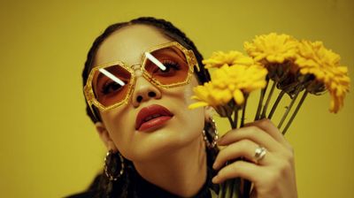 a woman wearing sunglasses holding a bunch of flowers
