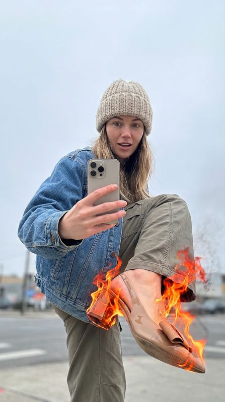 a woman holding a cell phone in front of a fire