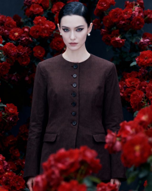 a woman standing in front of red flowers