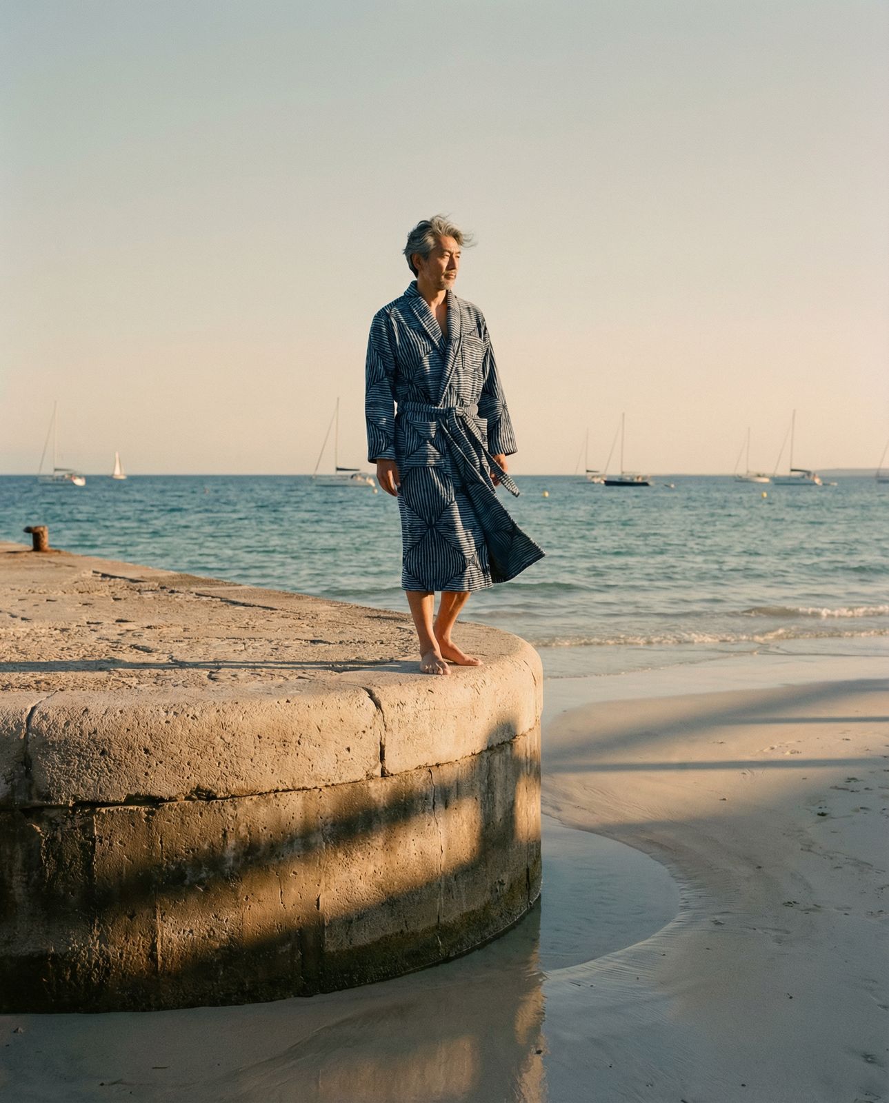 a man standing on a cement wall near the ocean