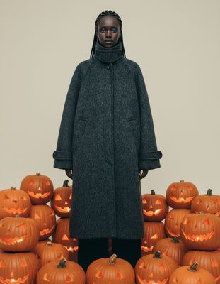 a woman standing in front of a pile of pumpkins