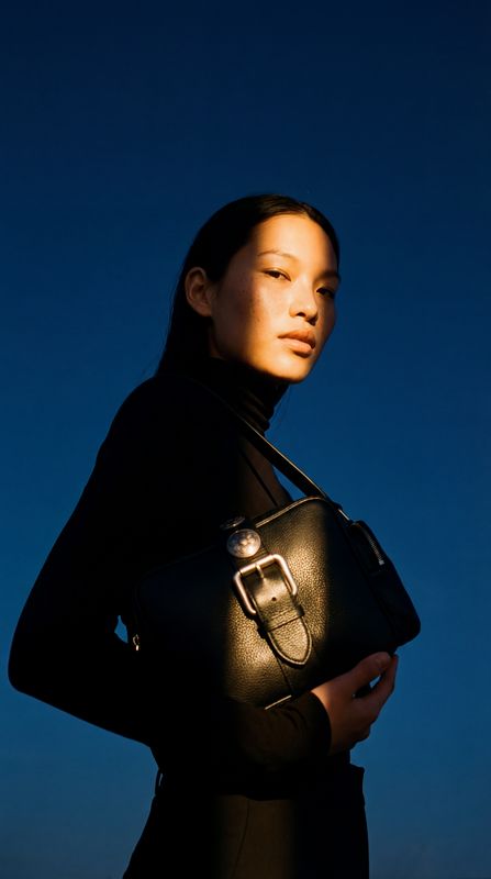 a woman in a black dress holding a black purse