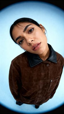 a woman with a brown jacket and a blue background