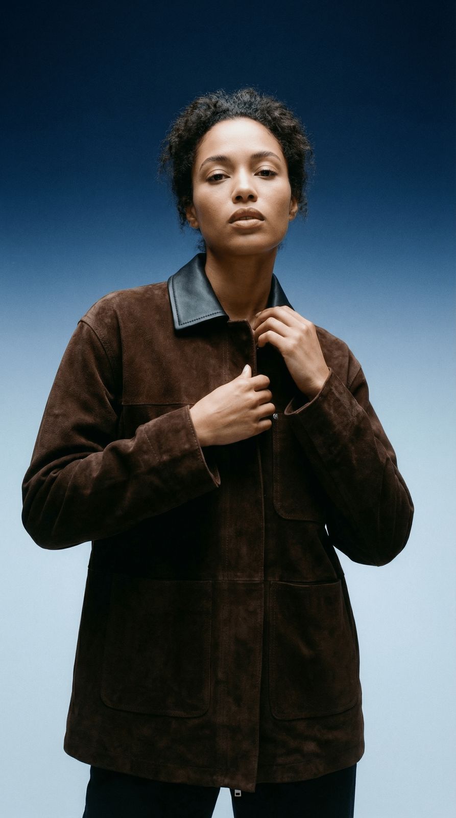 a woman in a brown jacket and black pants