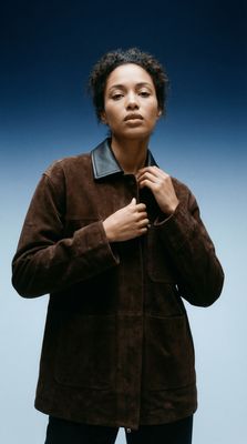 a woman in a brown jacket and black pants