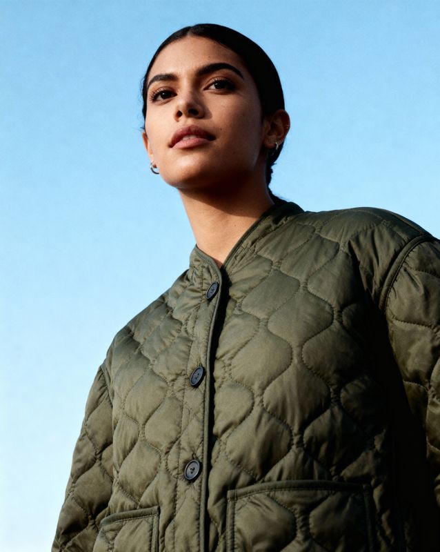 a woman in a green jacket looking off into the distance