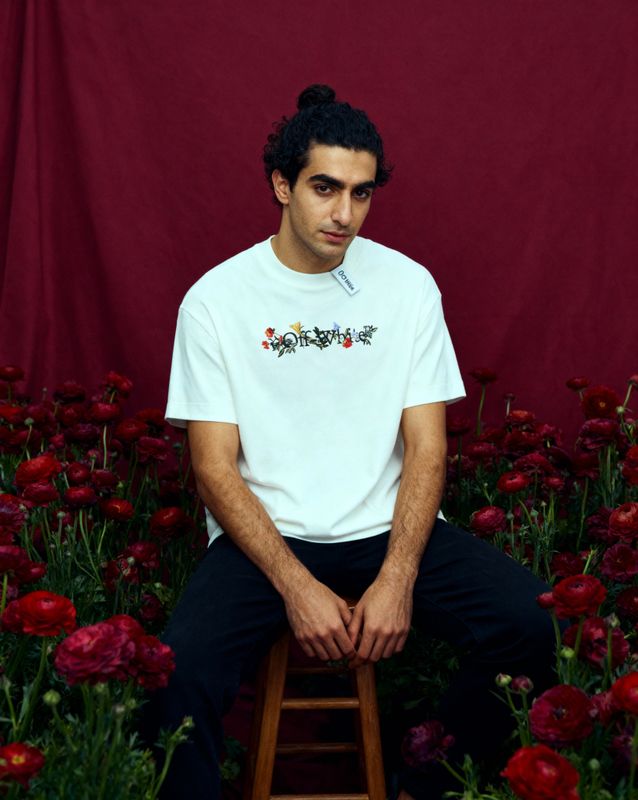 a man sitting on a stool in front of flowers