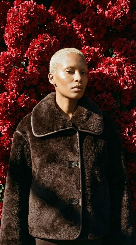 a woman standing in front of a bush of flowers