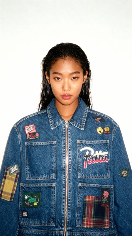 a woman wearing a jean jacket with patches on it