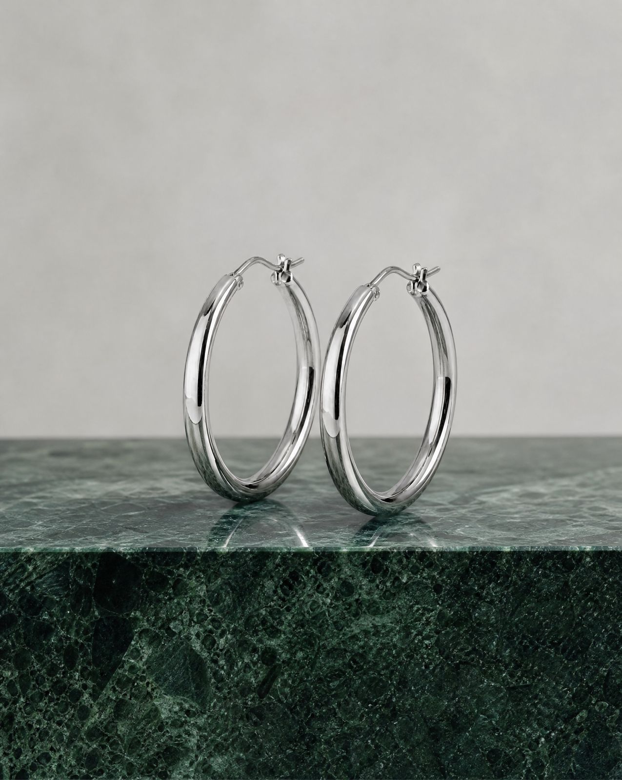 a pair of silver hoop earrings on a marble surface
