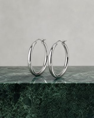 a pair of silver hoop earrings on a marble surface