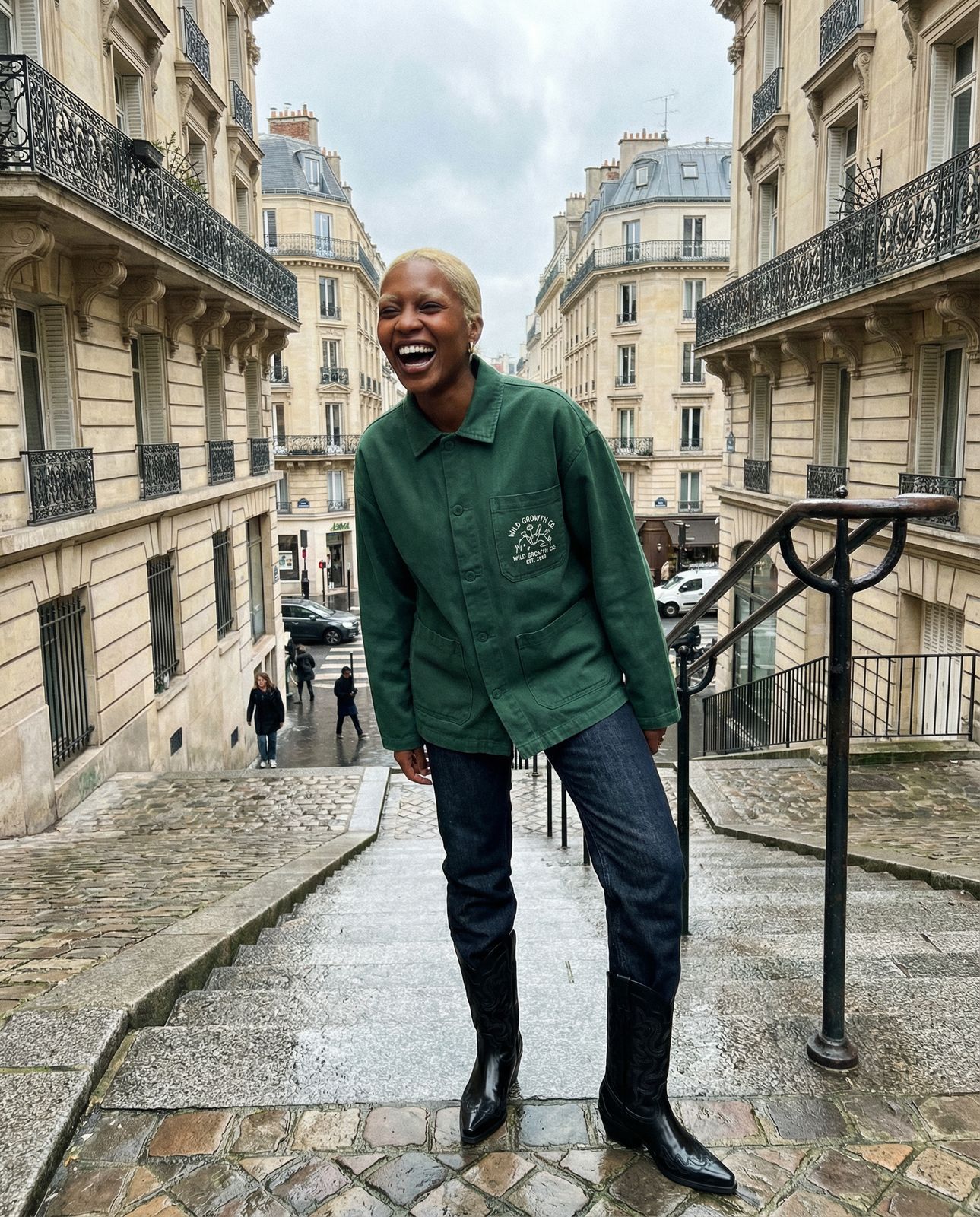 a man in a green jacket standing on a cobblestone street