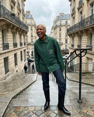 a man in a green jacket standing on a cobblestone street