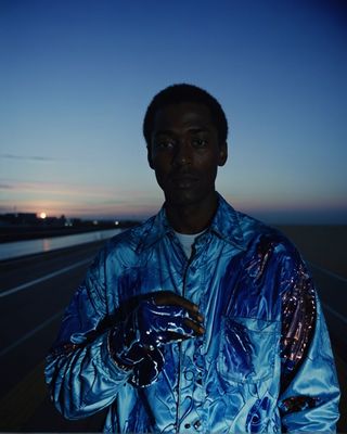 a man in a shiny blue jacket is holding something