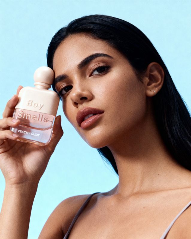 a woman holding a bottle of perfume in front of her face