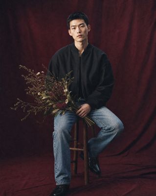 a man sitting on a stool holding a bouquet of flowers