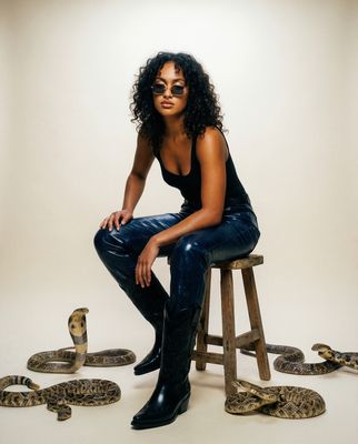 a woman sitting on a stool with snakes around her