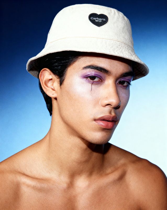 a shirtless man wearing a white hat and purple eye makeup