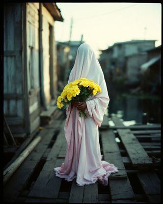 a woman in a pink dress holding a bouquet of yellow flowers