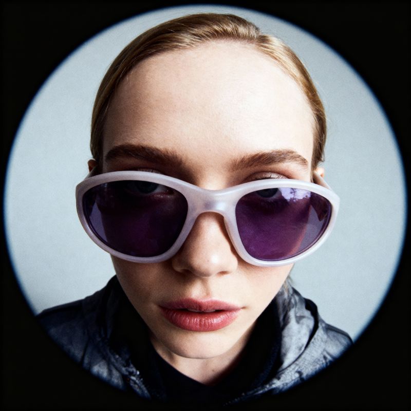 a woman wearing white sunglasses and a black jacket