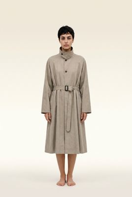 a woman in a trench coat standing in front of a white background