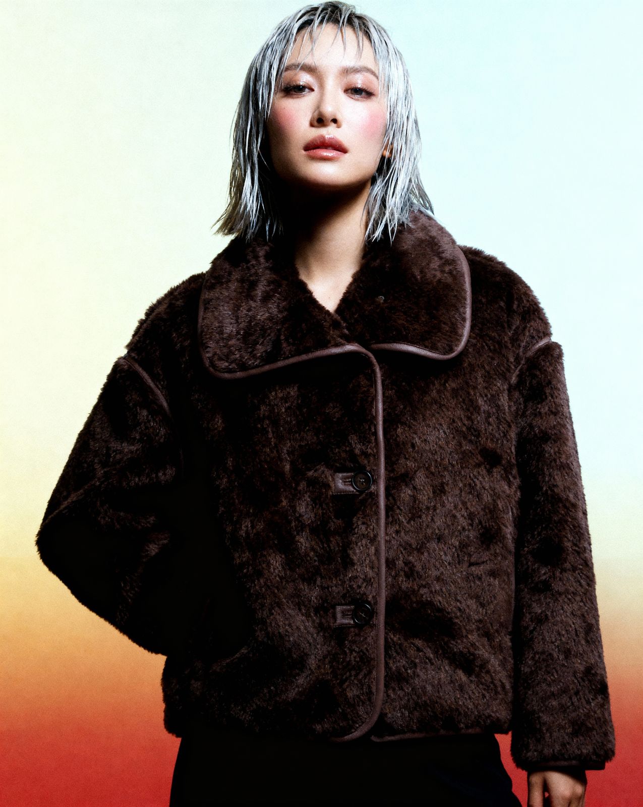 a woman with white hair wearing a brown coat