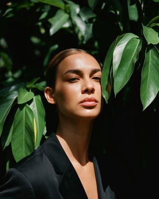 a woman standing in front of a tree with her eyes closed
