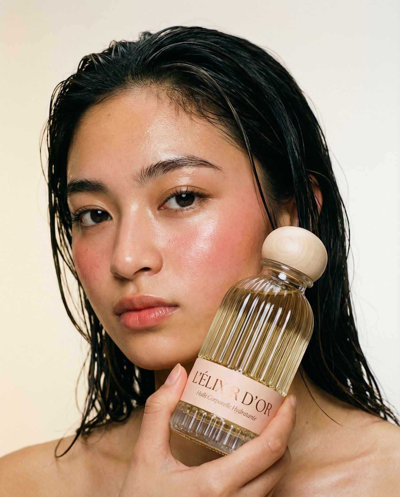 a woman holding a bottle of perfume in front of her face