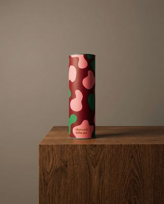 a pink and green vase sitting on top of a wooden table