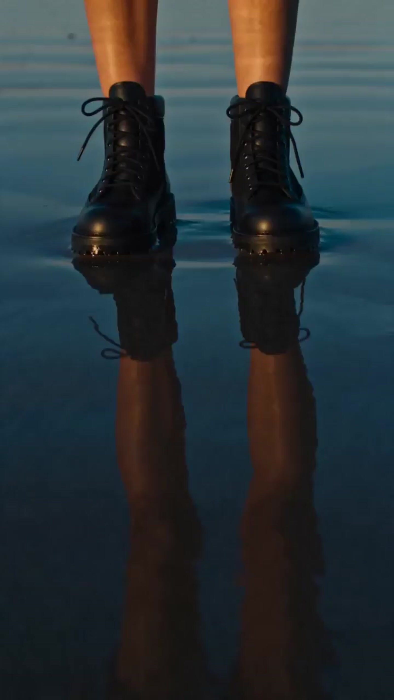 a person standing in the water wearing black shoes
