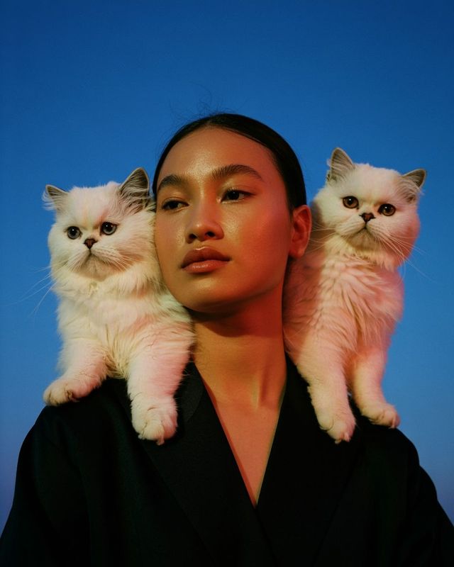 a woman with two cats on her shoulders