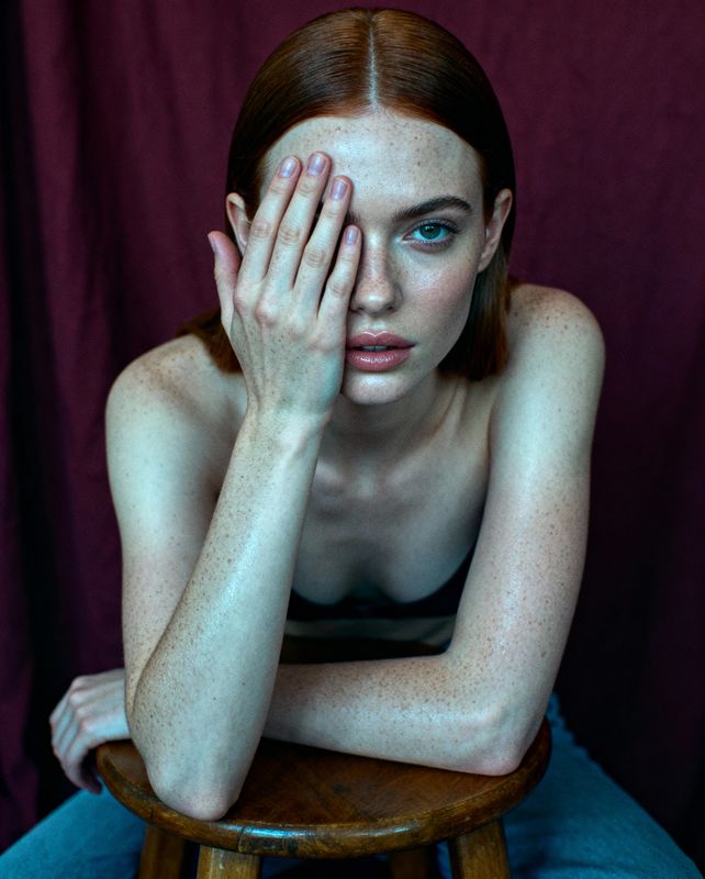 a woman sitting on a stool with her hands on her face
