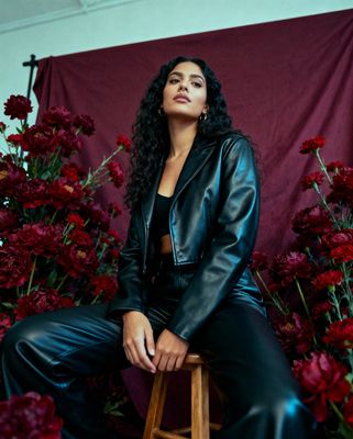 a woman sitting on a stool in front of flowers