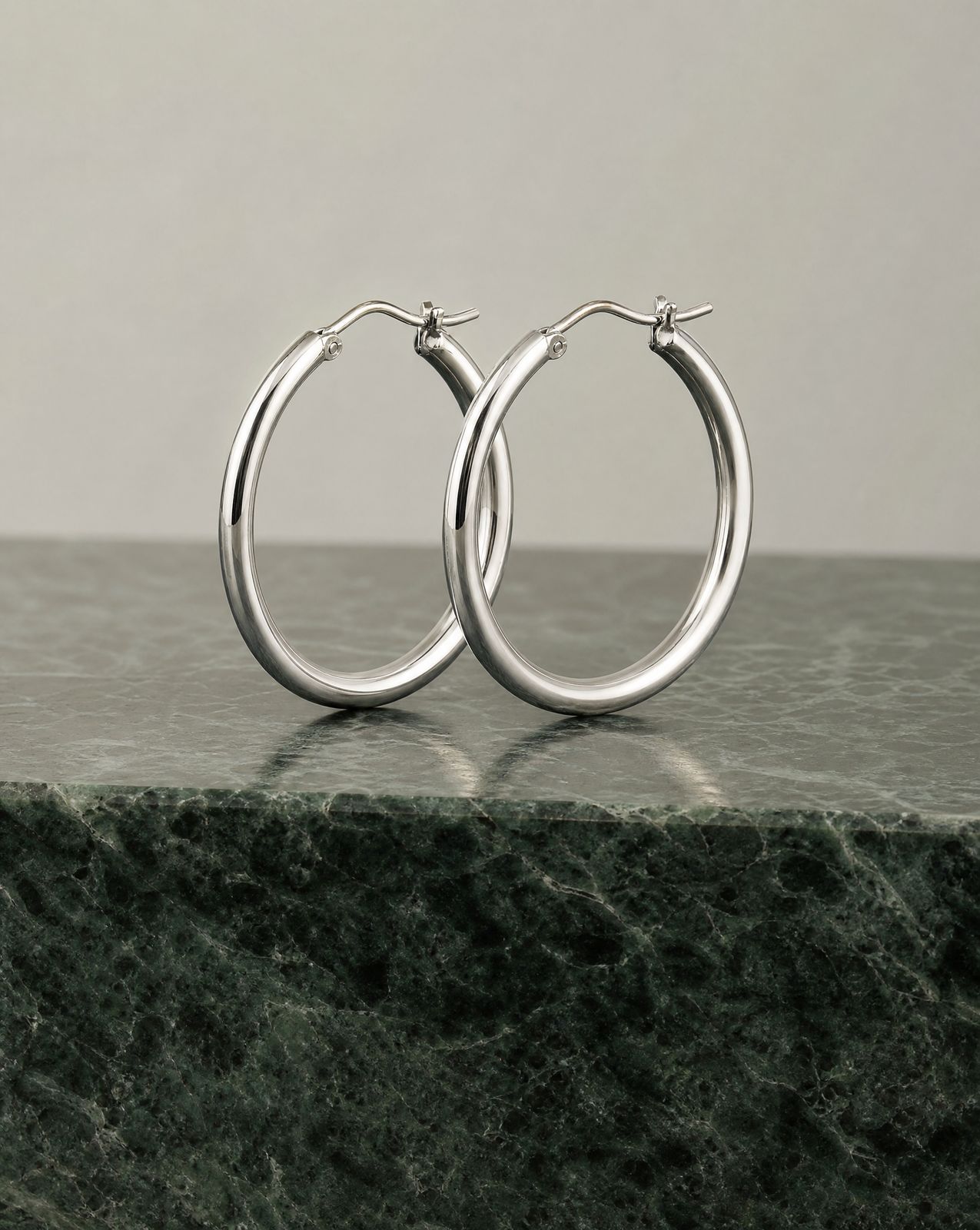 a pair of silver hoop earrings on a marble surface